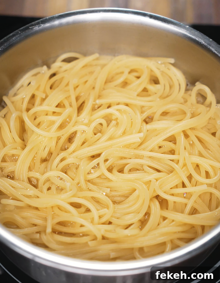 Spaghetti boiling in a stainless steel pot, cooked until al dente for the chili oil pasta.
