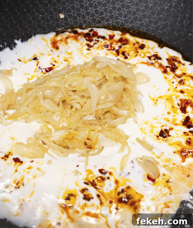 Caramelized onions added to a creamy chili oil sauce in a pan to build the flavor base.