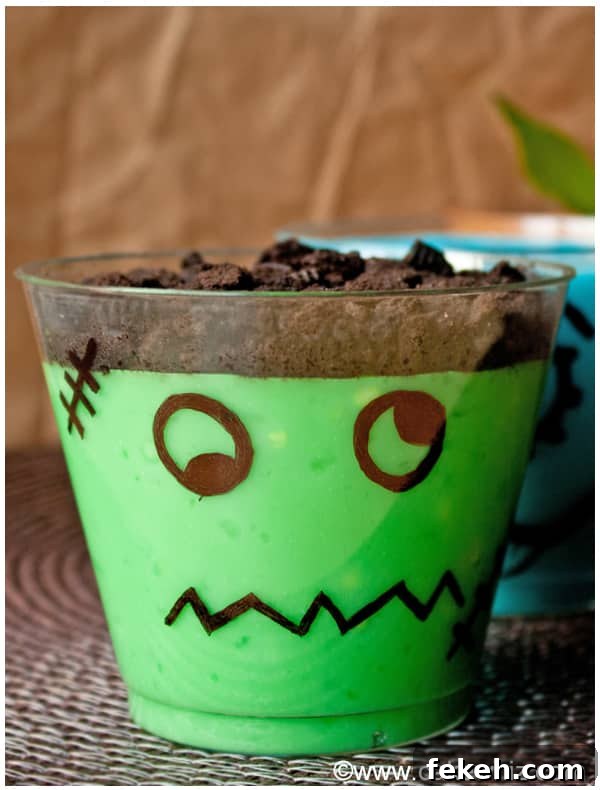 Halloween Pudding Cups: Spooky Dessert Cups for Party Treats 3 Frankenstein Pudding Cups on Brown Background