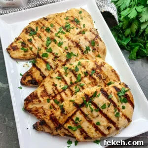 Honey Mustard Grilled Chicken Recipe for Juicy, Tangy Flavor 6 Honey mustard grilled chicken on a white plate garnished with fresh chopped parsley.