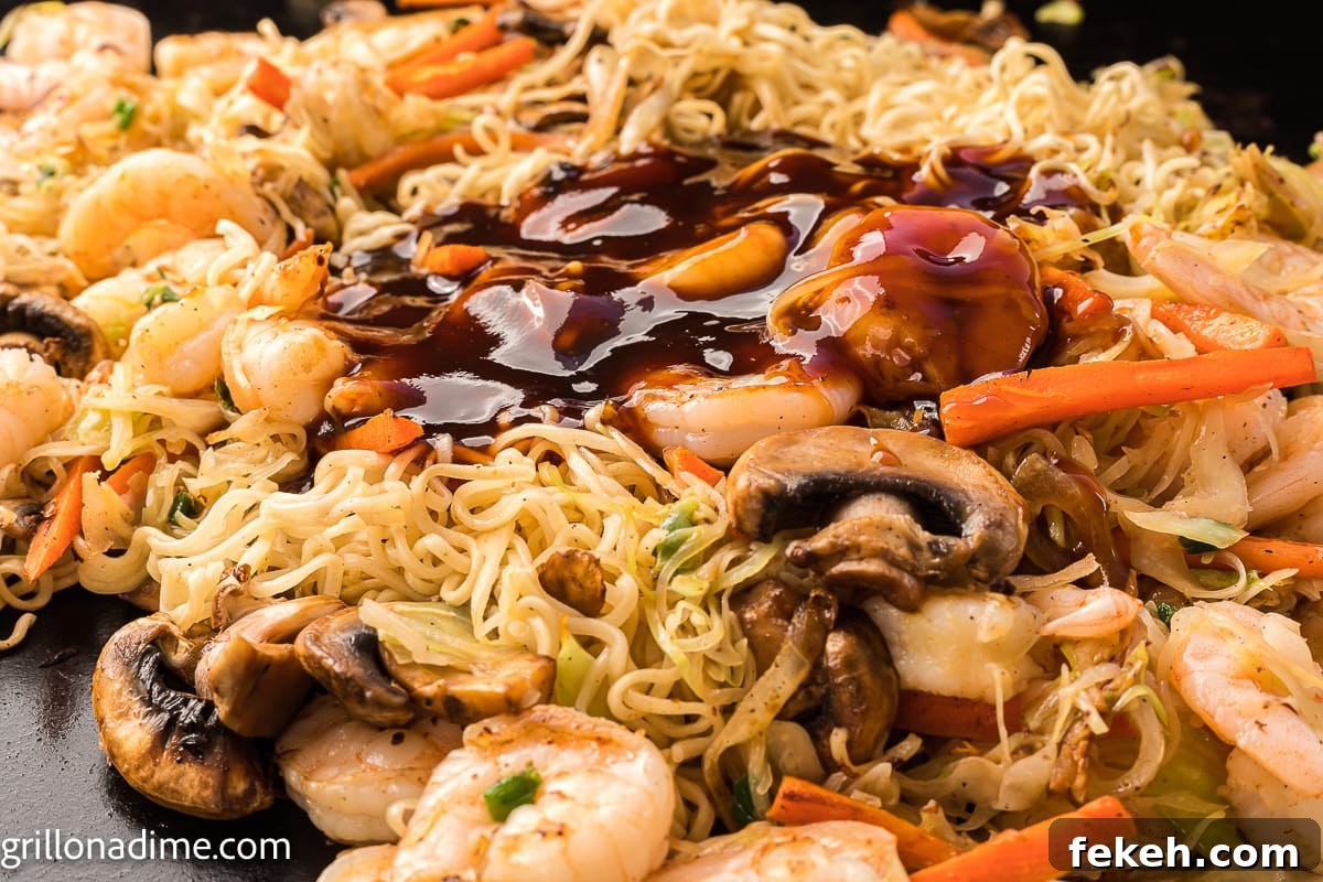 Blackstone Shrimp Yakisoba Recipe — Quick Griddle Noodle Stir-Fry 7 Cooked noodles, slice mushrooms, cooked shrimp and carrots on the griddle