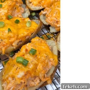 Buffalo Chicken Twice-Baked Potatoes — Tangy Loaded Potato Recipe 5 Close-up of Buffalo Chicken Twice Baked Potatoes topped with melted cheddar cheese, shredded chicken, and sliced green onions, resting on a wire rack.