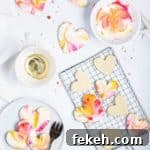 iced valentine cookies on a cooling rack with a bowl of icing next to them