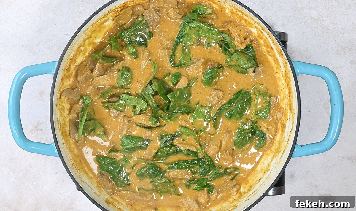Leftover Turkey Curry Recipe for a Flavorful Dinner 8 curry cooking in a skillet with spinach leaves