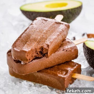 3 healthy fudgicles piled up, with a bite taken out of top one and an avocado in the backgground