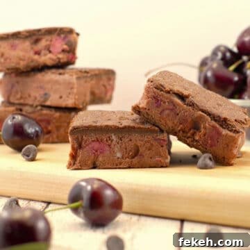 WW black forest ice cream sandwiches on cutting board with more stacked in back and bowl of cherries in background
