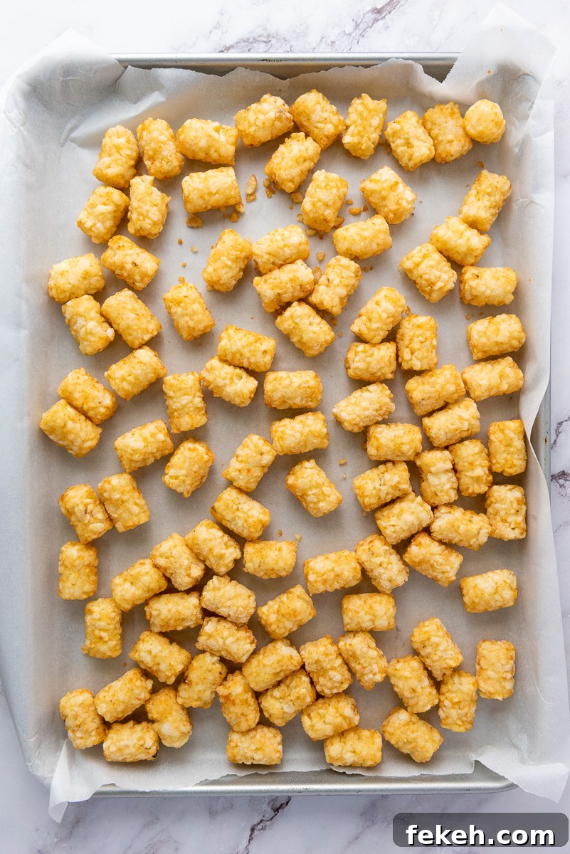 Cheesy Bacon Loaded Tater Tot Nachos (Totchos) 5 Tater tots spread in single layer on baking sheet ready to go into the oven.