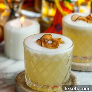 A beautiful cocktail with a foam top, garnished with a dried pear.
