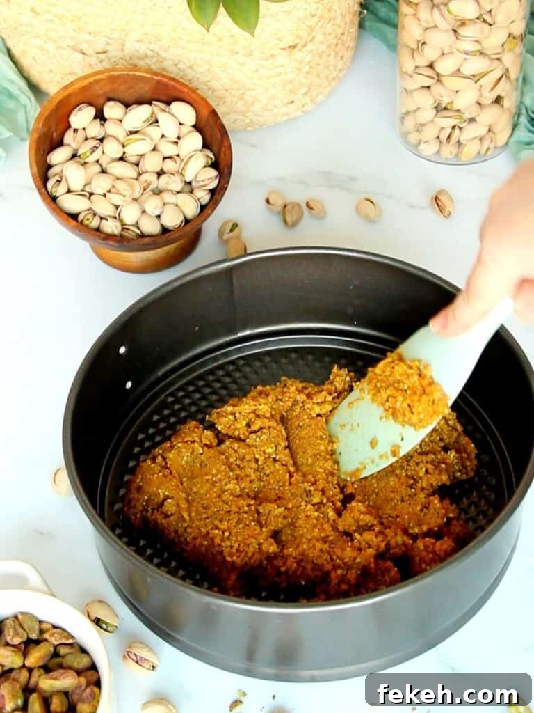 Creamy Pistachio Cheesecake with Real Pistachios and Homemade Paste 7 Tapping Graham crumbs into a pan