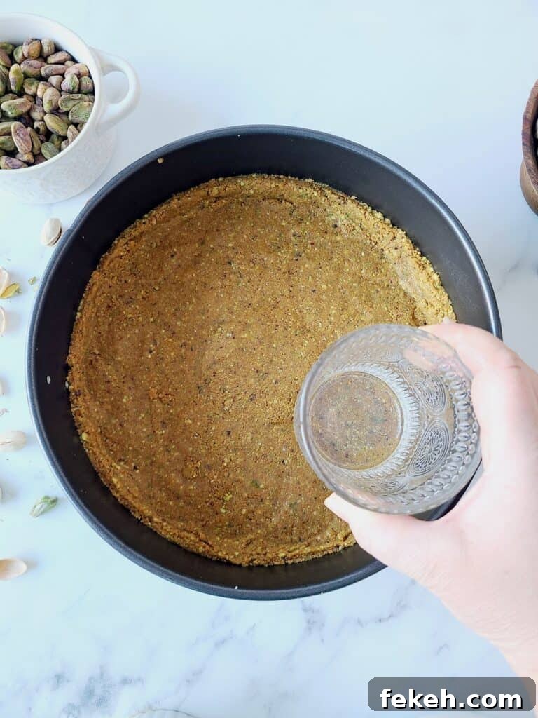 Creamy Pistachio Cheesecake with Real Pistachios and Homemade Paste 8 Tapping with glass the mixture for graham cracker's crust into a pan