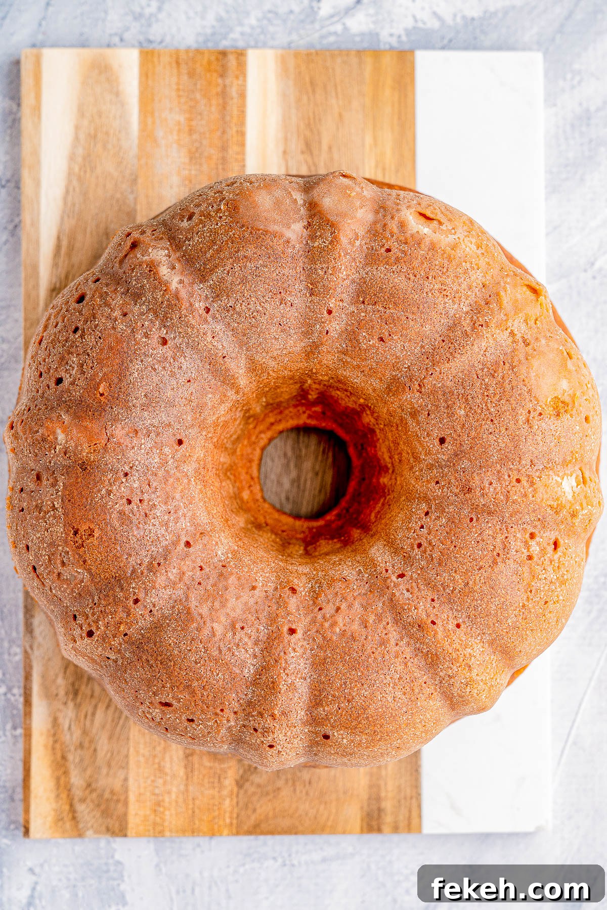 Classic Cream Cheese Pound Cake Recipe for Moist, Tender Slices 13 A bundt cake with a light brown crust on a wooden cutting board.