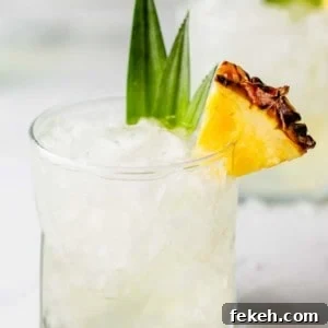 Pineapple vodka in a rocks glass, garnished with a slice of pineapple