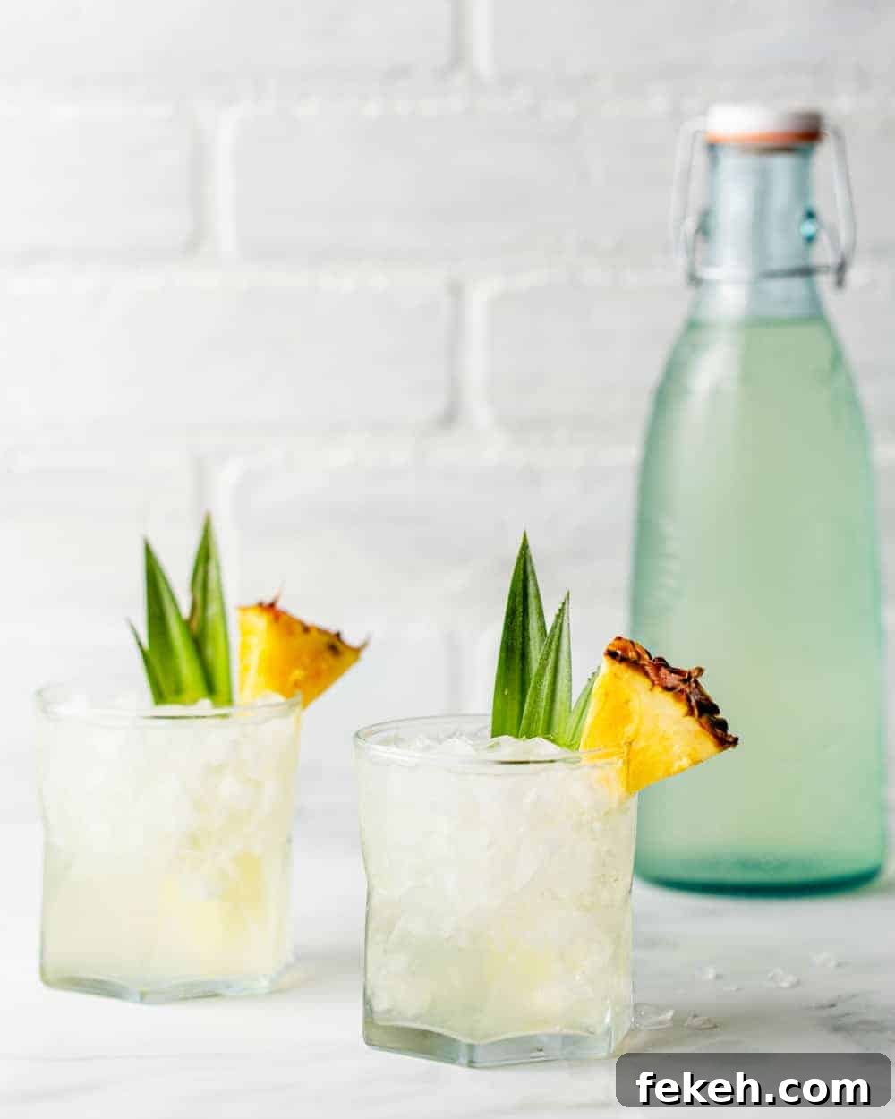 How to Make Stoli Doli: Puerto Rican Coconut Rum Dessert Recipe 8 Two Stoli Doli cocktails in rocks glasses next to a bottle of infused pineapple vodka