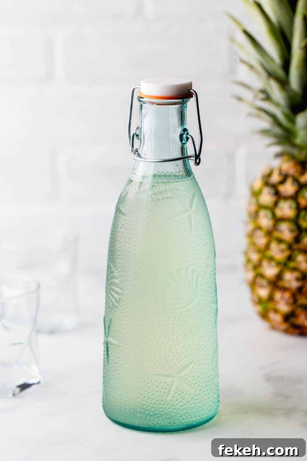 How to Make Stoli Doli: Puerto Rican Coconut Rum Dessert Recipe 9 Bottle of pineapple-infused vodka with a pineapple in the background