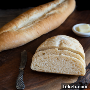 Authentic Cuban Bread (Pan Cubano) Recipe for Crispy Loaf 14 Angled view of a Cuban baguette with two slices leaning on the loaf. Hostess At Heart