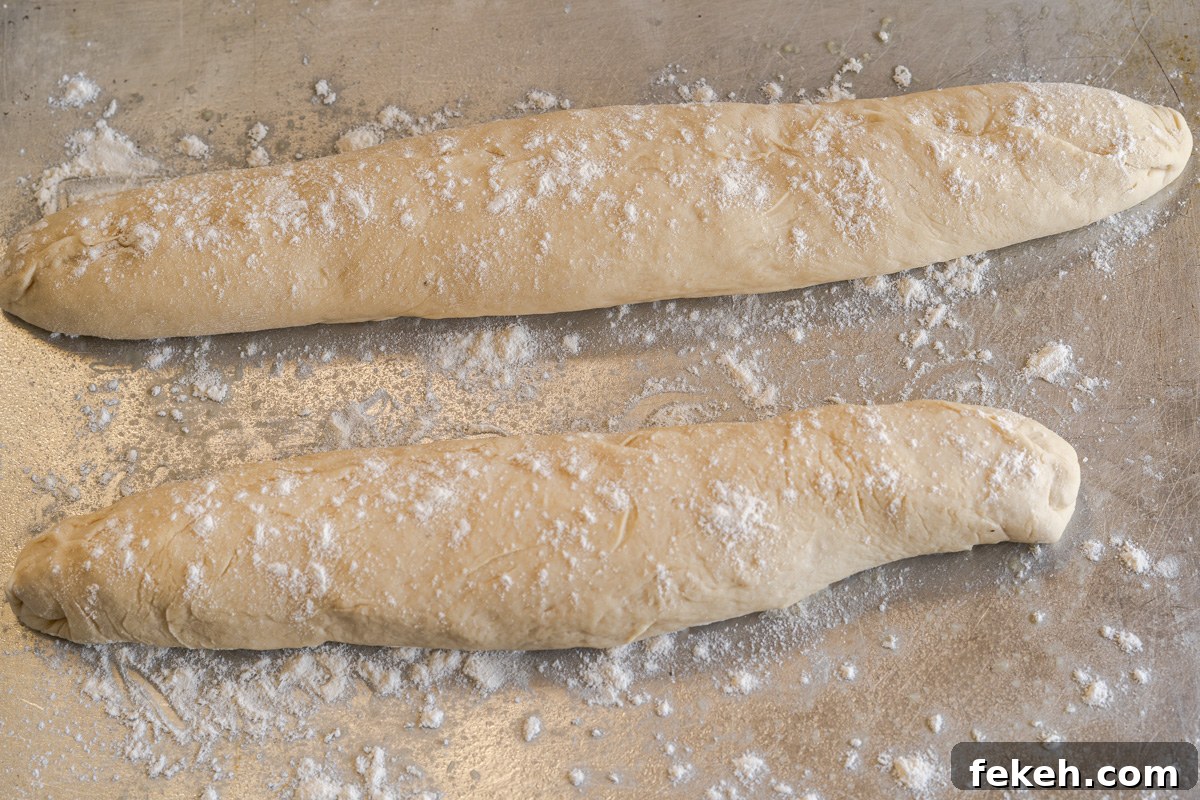 Authentic Cuban Bread (Pan Cubano) Recipe for Crispy Loaf 10 Two baguettes dusted with flour sitting on a baking sheet - Hostess At Heart
