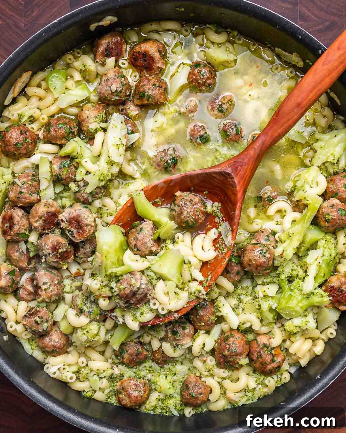 Macaroni and Broccoli with Mini Meatballs Recipe 8 Overhead shot of large pan with pasta broccoli and tiny meatballs with large wooden spoon.
