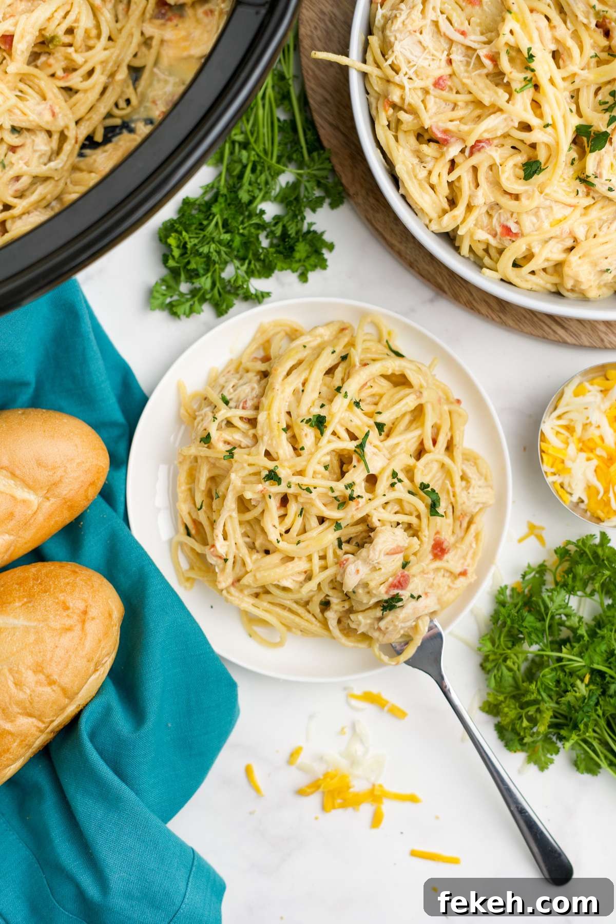 A plate of crockpot chicken spaghetti on the table with a fork to the side.