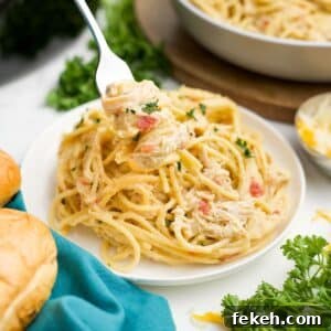 Slow cooker chicken spaghetti served up on a plate with a fork lifting up a bite.