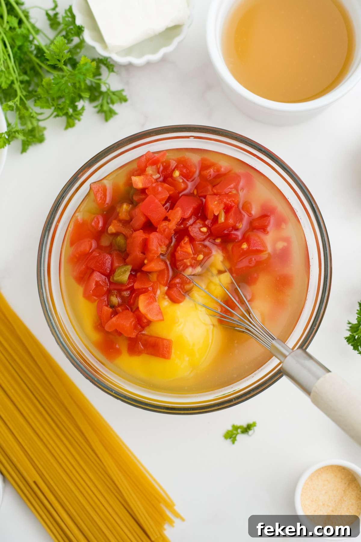 Ingredients to make the sauce in a bowl on the table with a whisk in the bowl.
