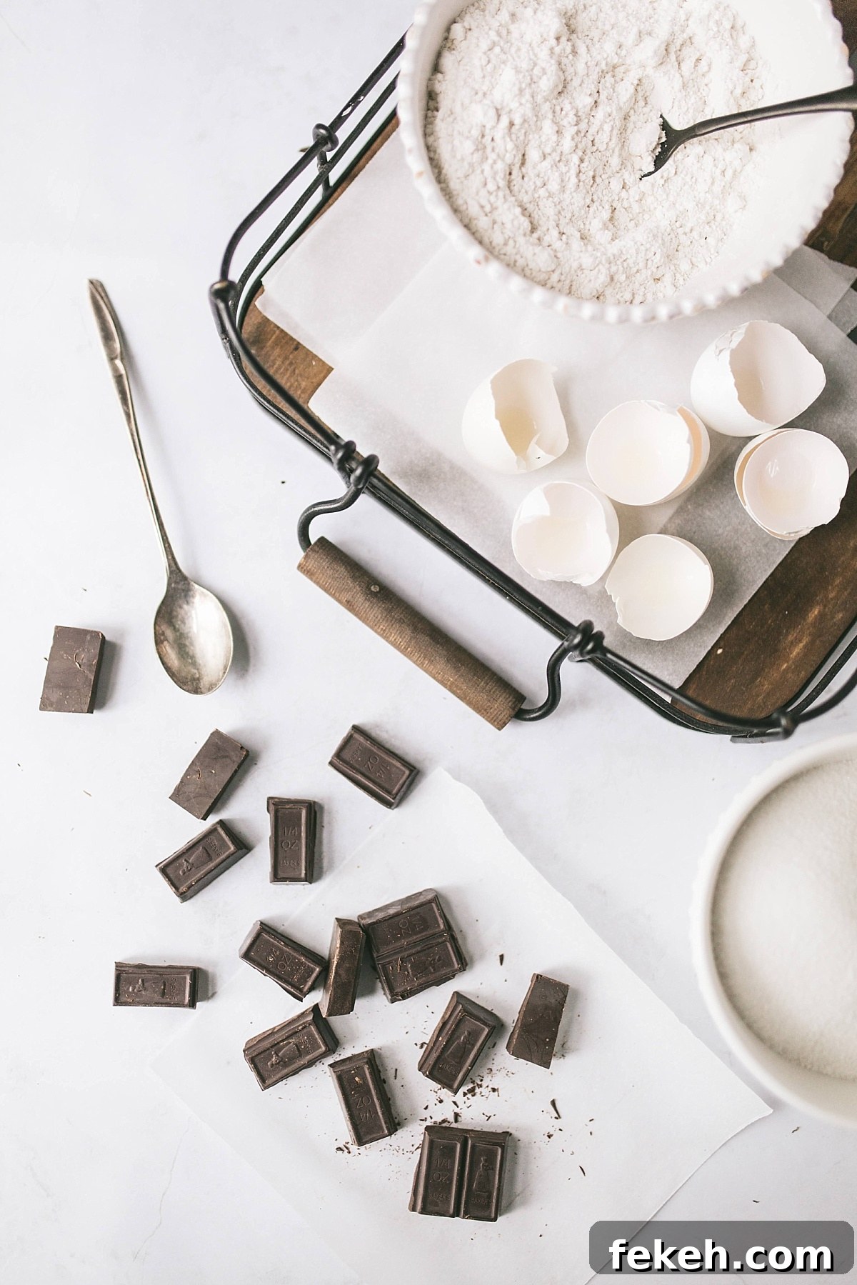 broken eggshells, bowl of flour, and chunks of unsweetened bakers chocolate