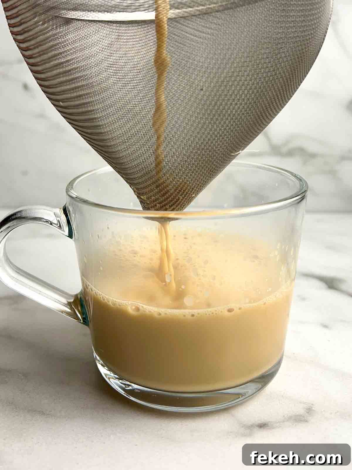 Chinese Ginger Milk Tea Recipe: Authentic Hot Drink with Fresh Ginger 7 ginger milk tea being strained into glass cup.