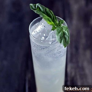 Smoked Tom Collins with Basil-Smoked Simple Syrup 4 tall narrow glass of smoked tom collins with basil sprig