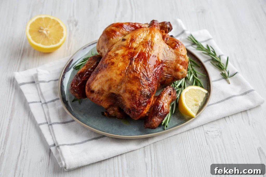 rotisserie chicken on a plate with lemon wedges and fresh herbs