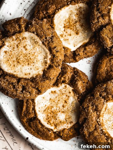Pumpkin cookies with cream cheese centers on a white speckled ceramic platter.