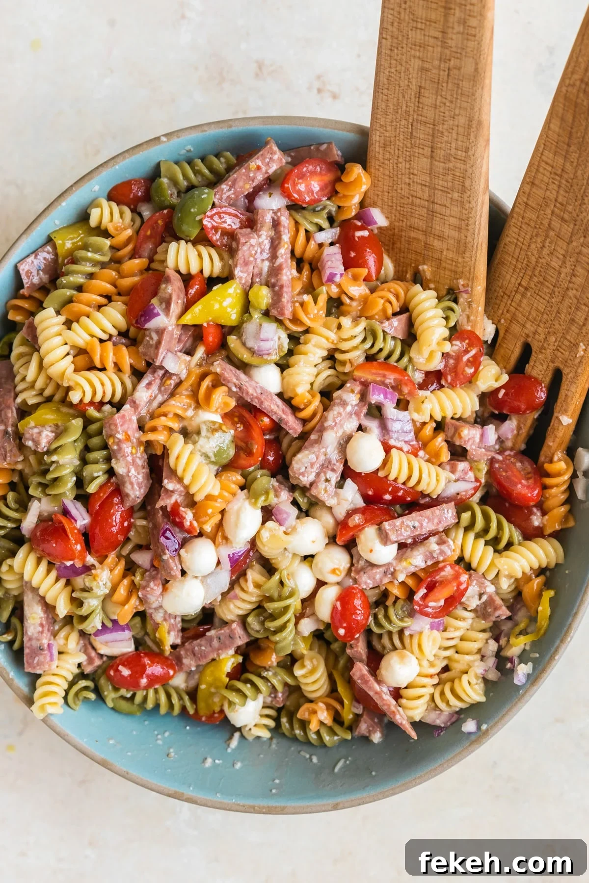 Quick Italian Pasta Salad Recipe for Summer Potlucks 5 pasta in a bowl with sausage and tomatoes and cheese.
