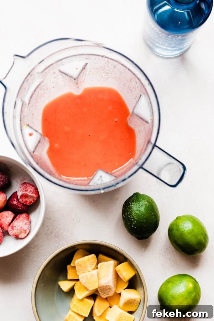 The pinky orange cocktail mixture blended up in the blender, with fruit scattered around