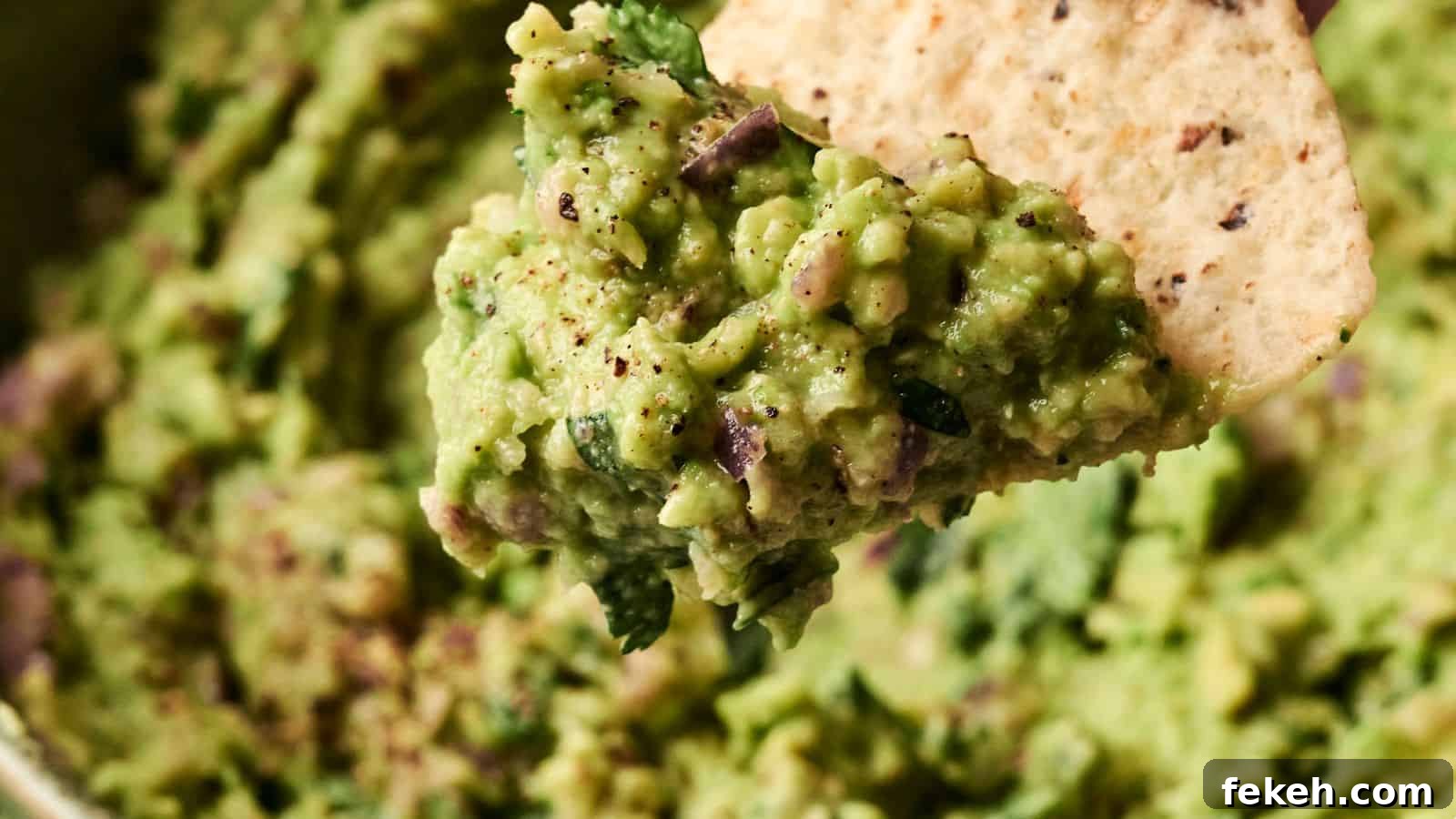 I Tried 15 Fall Snacks So You Don’t Have To — Top Picks Reviewed 8 Close-up of guacamole on a tortilla chip, showing a textured mixture of avocado, herbs, and spices.
