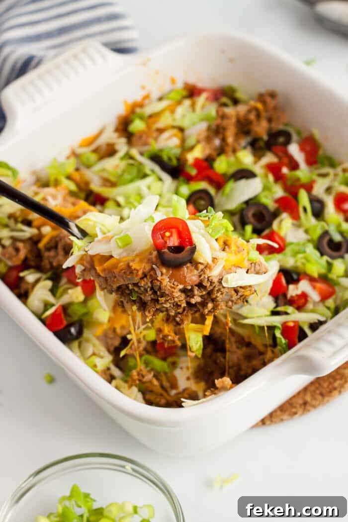 Low-Carb Keto Taco Salad Recipe for Quick Weeknight Meals 8 white casserole dish with spoon scooping out low carb taco casserole piece