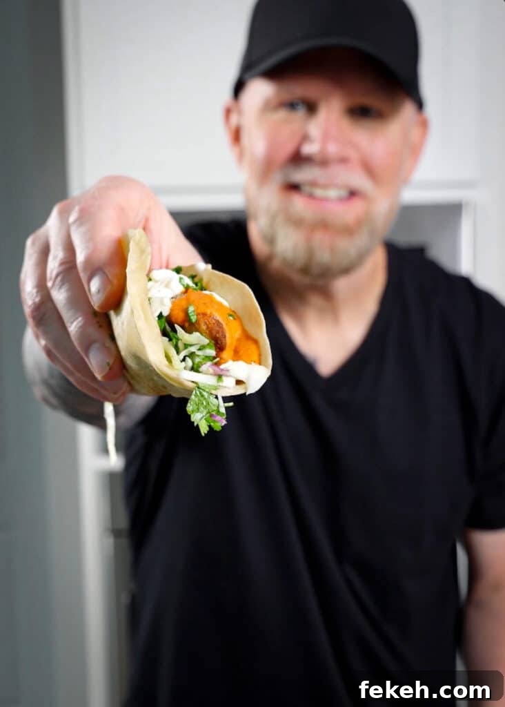 Chicken Tikka Masala Tacos Recipe — Fusion Indian Street Food 2 man in a black tee shirt holding a taco for the camera