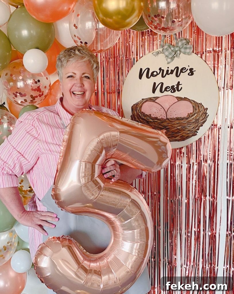 Celebrating My 5-Year Blogiversary: Highlights & Milestones 2 Norine holding a large number 5 balloon with a big balloon arch behind her and her logo.