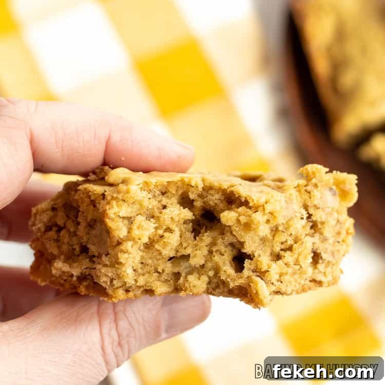Peanut Butter Banana Oat Oatmeal Bars — Chewy Snack Squares 12 hand holding one of the peanut butter banana oatmeal bars