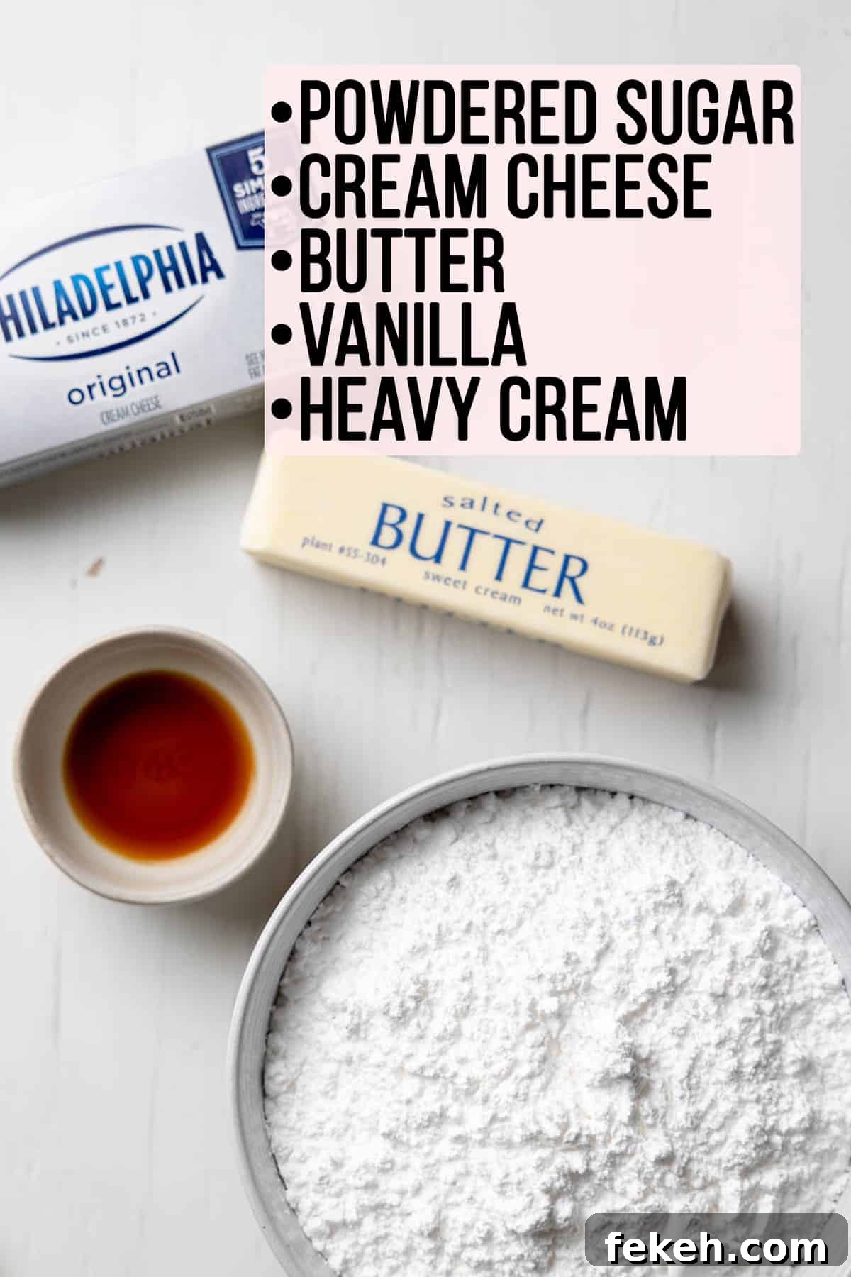 Cream cheese, butter, powdered sugar and vanilla measured out in bowls on a white surface.