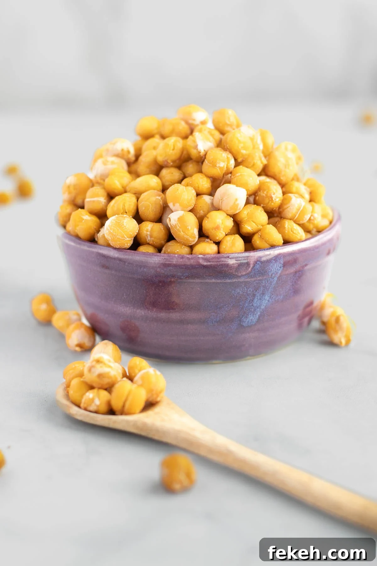 Crunchy roasted chickpeas in a purple bowl. A spoonful close up in front of the bowl.