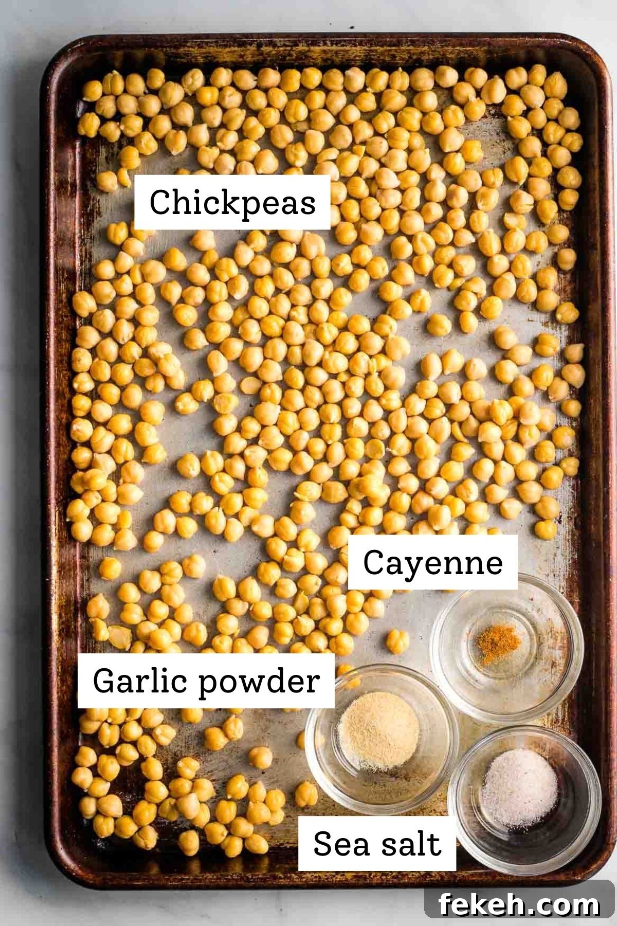 Labeled ingredients on a baking sheet: chickpeas, garlic powder, cayenne, sea salt.