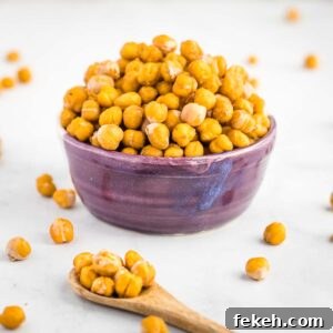 Crunchy chickpeas piled into a purple bowl with a spoon of them in the foreground.