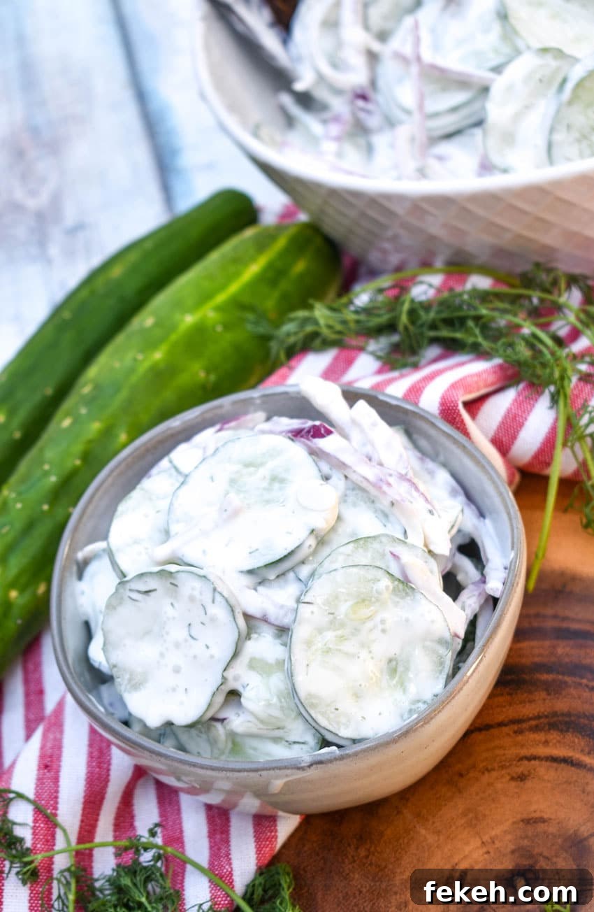 Creamy Cucumber Salad Recipe with Dill and Sour Cream 6 creamy cucumber salad in a small gray bowl on a wooden cutting board