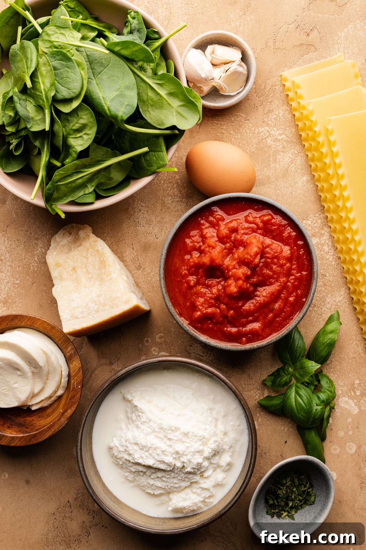 Creamy Spinach Lasagna Recipe with Ricotta and Mozzarella 3 Ingredients for spinach lasagna arranged on a tan-colored background.