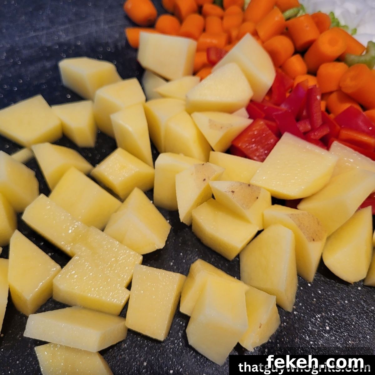 Creamy Smoked Salmon Chowder Recipe for Cozy Weeknight Dinners 4 diced gold peppers, carrots, red bell pepeprs, celery and white onions on a black cutting board