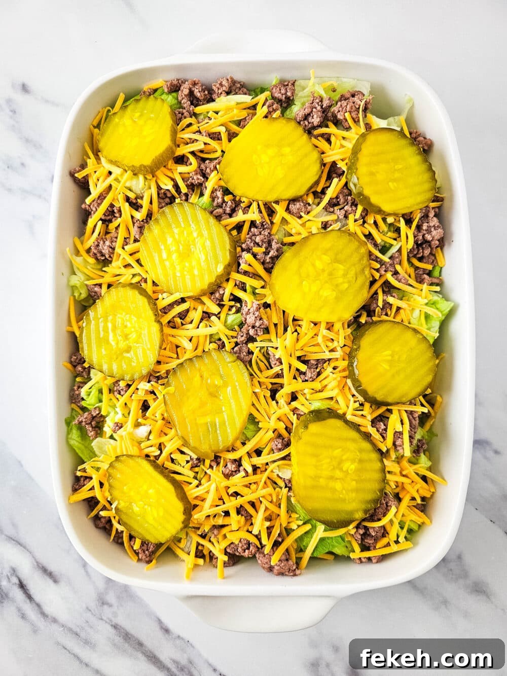 Keto Big Mac Salad: High-Protein Low-Carb Cheeseburger Bowl 11 chopped lettuce and ground beef and shredded cheese and pickles in a casserole dish