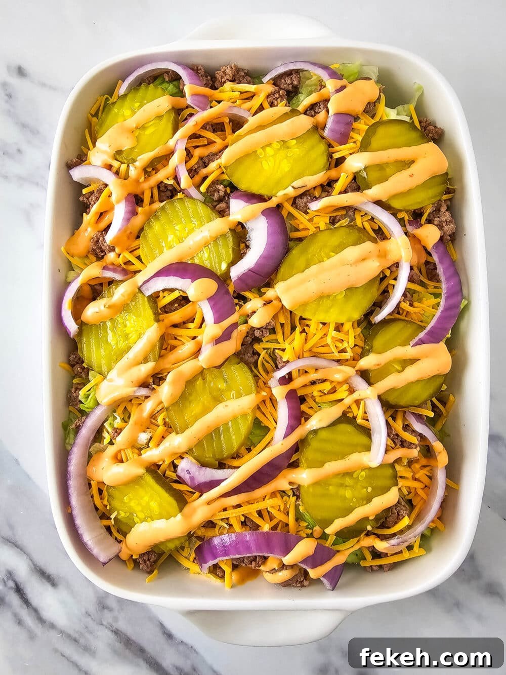 Keto Big Mac Salad: High-Protein Low-Carb Cheeseburger Bowl 13 chopped lettuce and ground beef and shredded cheese and pickles and onions and thousand island dressing in a casserole dish