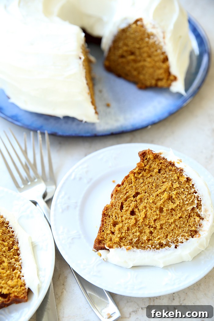 A round platter with a pumpkin bundt cake with cream cheese frosting with a couple slices cut out, and a slice of pumpkin cake on a dessert plate with two forks sitting crisscross on each other on the left.