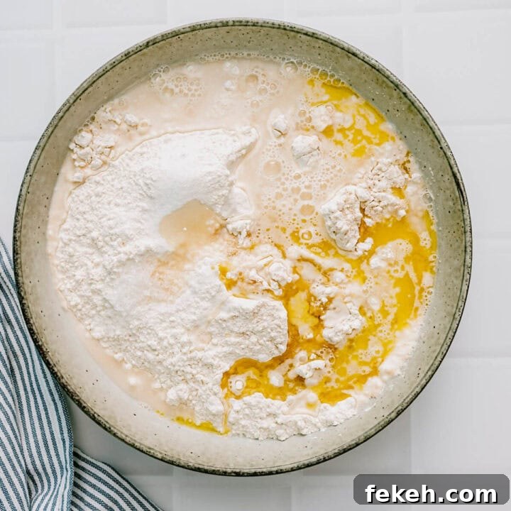 Authentic Greek Pita Bread Recipe: Soft, Foldable Pitas 5 Flour, yeast, olive oil and water being combined in a ceramic bowl to make pita dough.