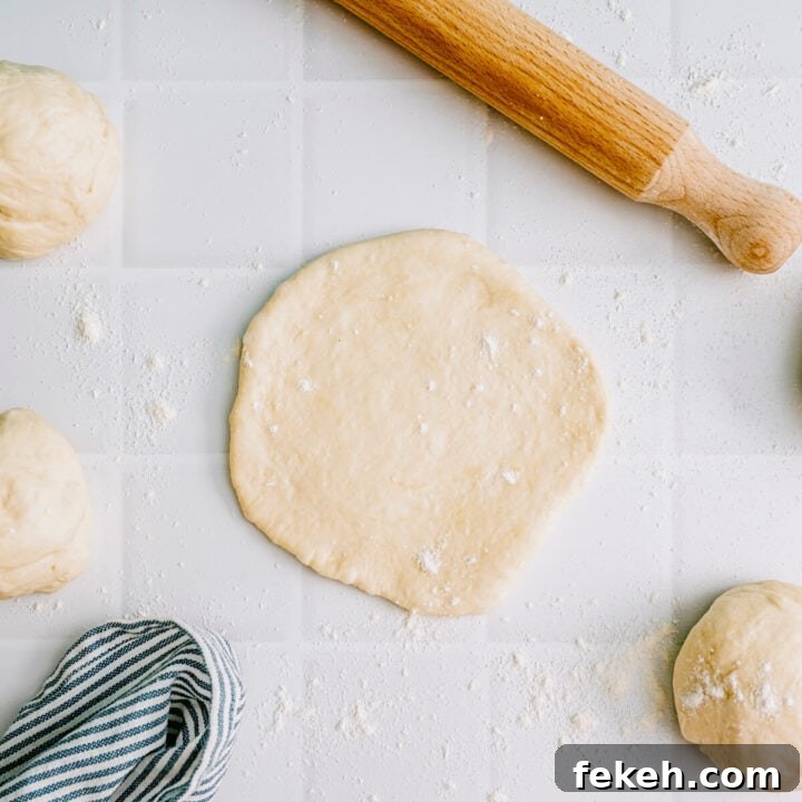 Authentic Greek Pita Bread Recipe: Soft, Foldable Pitas 7 Greek pita dough rolled into a round shape ready for cooking.