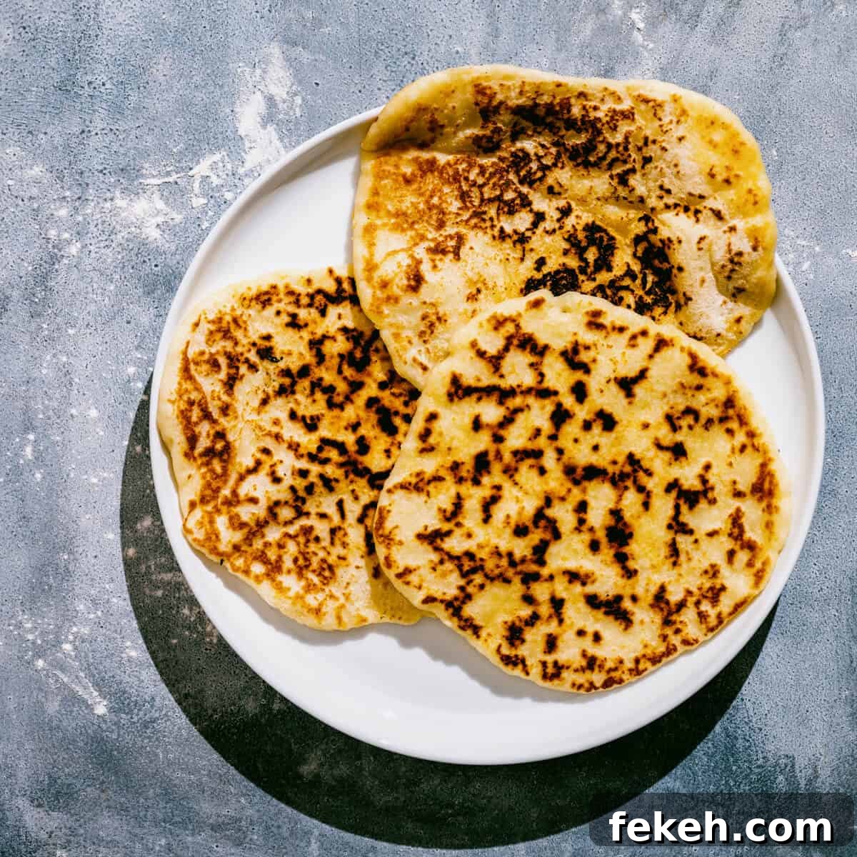 Authentic Greek Pita Bread Recipe: Soft, Foldable Pitas 9 a whiter plate with 3 Greek yogurt flatbreads.