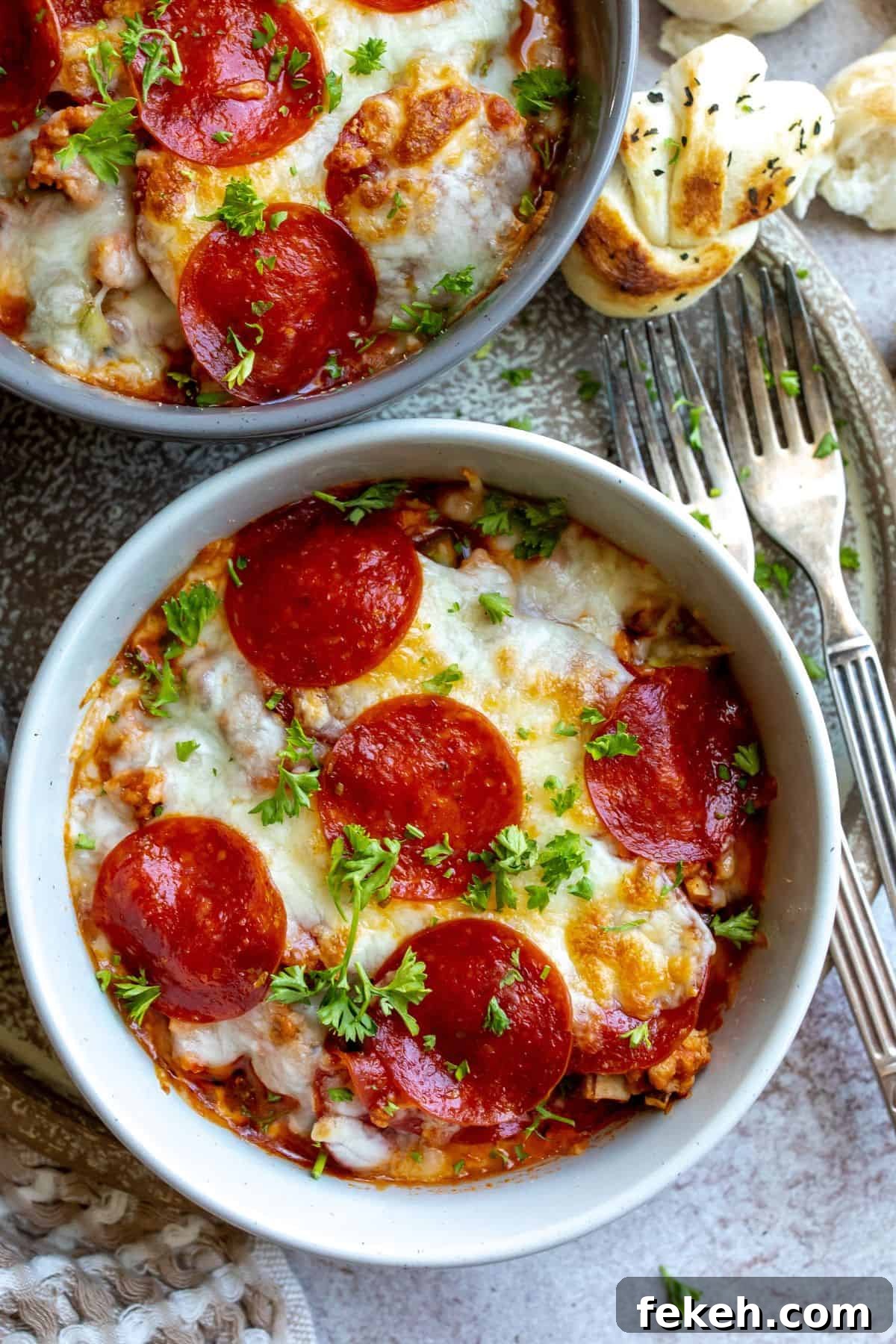 Creative Pizza Bowl Recipes: Flavorful Mini Pizza Bowls for Any Meal 2 Pizza bowls in an oven safe ceramic bowl with pepperoni toppings and cheese.